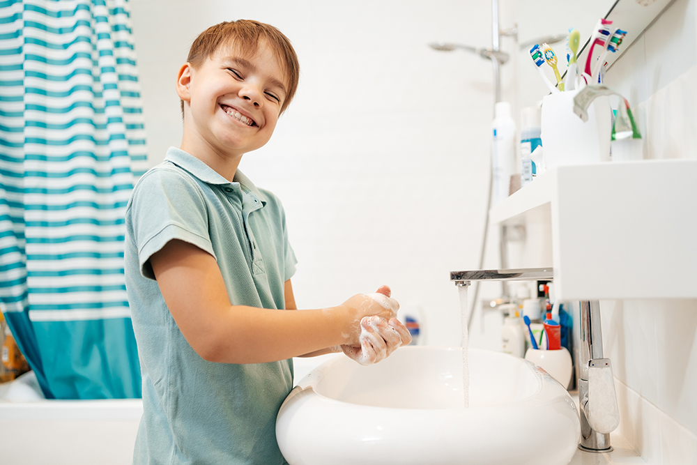 preschool smiling boy washing hands with soap faucet with water