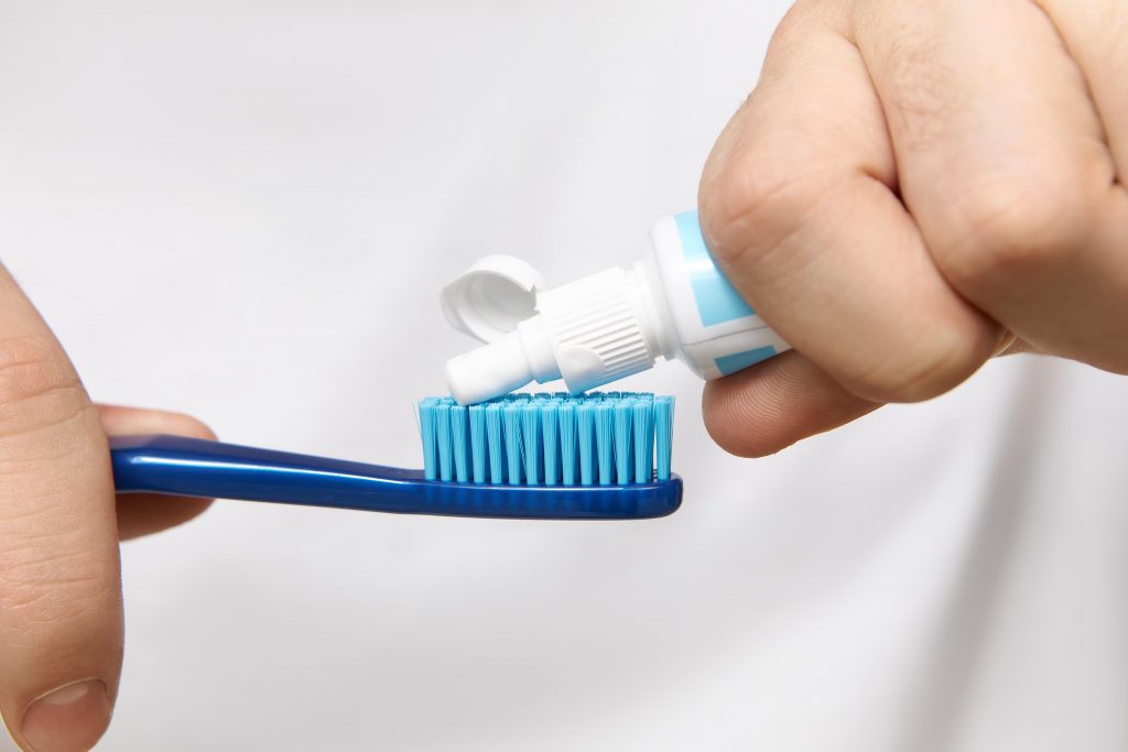 close up image man s hands holding tube squeezing whitening toothpaste brush