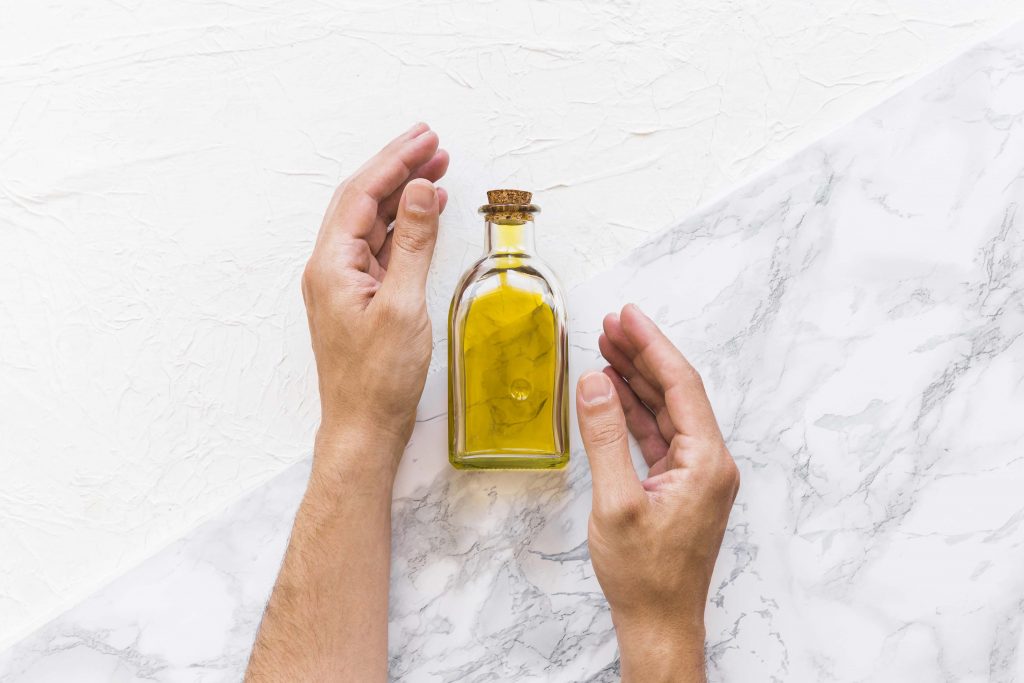 hands protecting oil bottle textured backdrop